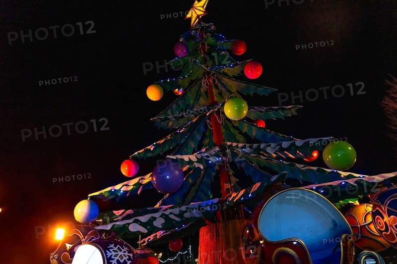 Colorful christmas tree with lights and decorations illuminating a carousel at night in bayonne, france, creating a festive atmosphere