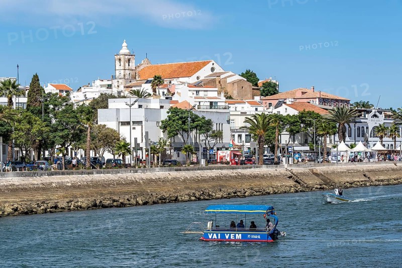 The skyline of the old town of Lagos, on the river Bensafrim, harbour canal, passenger ferry across the Vai Vem Balsa canal, in the west of the Algarve, Portugal