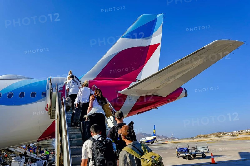 Mykonos, Greece - EUROWINGS. At Mykonos Airport, holidaymakers board a Eurowings aircraft via an external staircase on the apron. Behind them is a Ryanair aircraft