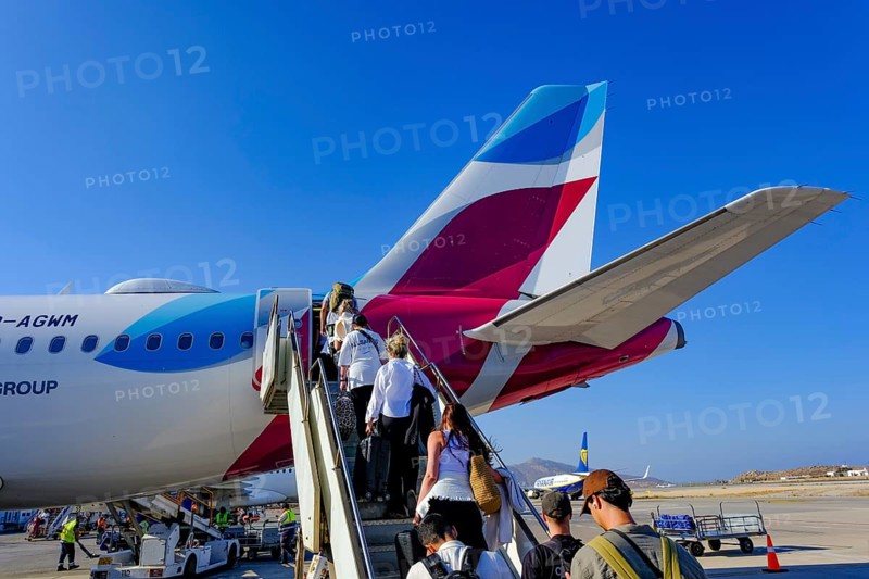 Mykonos, Greece - EUROWINGS. At Mykonos Airport, holidaymakers board a Eurowings aircraft via an external staircase on the apron. Behind them is a Ryanair aircraft