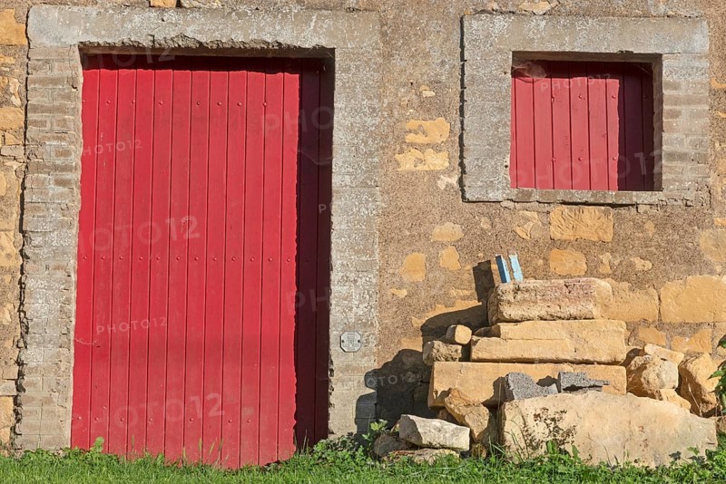 Red door and windows, historic house façade, yellow sandstone, Marville, Renaissance village, Département Meuse, Grand Est, France