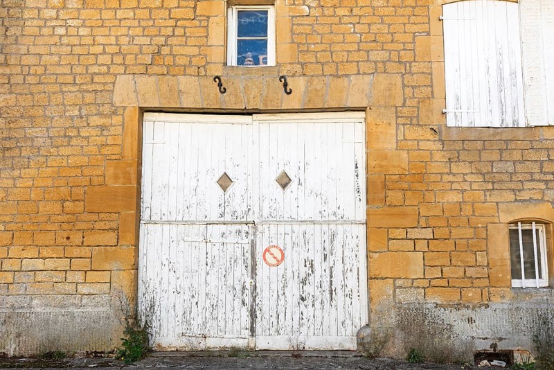 Closed white wooden door and windows, historic house façade, yellow sandstone, Marville, Renaissance village, Département Meuse, Grand Est, France