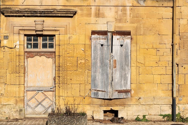 Closed wooden door and windows, historic house façade, yellow sandstone, Marville, Renaissance village, Département Meuse, Grand Est, France
