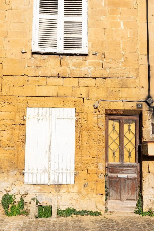 Closed door and white wooden window, historic house façade, yellow sandstone, Marville, Renaissance village, Département Meuse, Grand Est, France