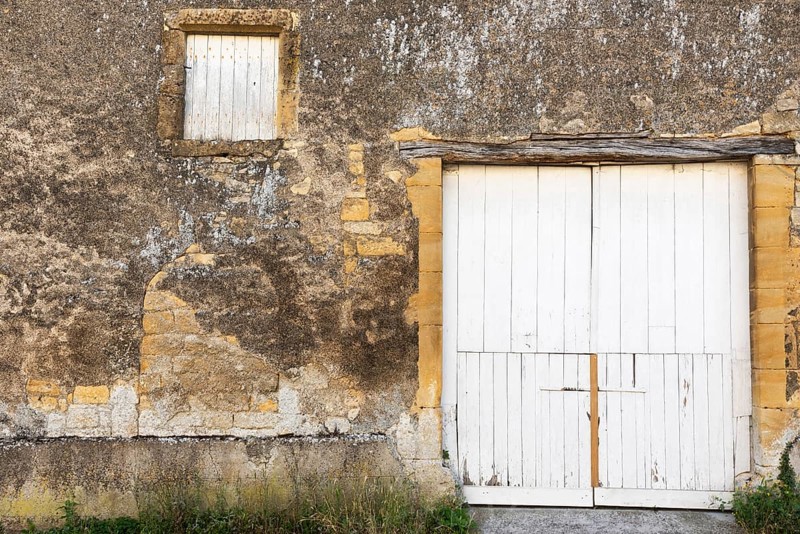 Closed white wooden door and windows, historic house façade, yellow sandstone, Marville, Renaissance village, Département Meuse, Grand Est, France