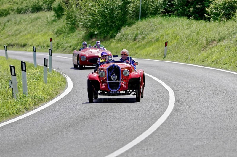 Red classic car in a sharp bend, followed by other classic cars on a country road, classic car, car race, Mille Miglia, 1000 Miglia, 2015, Tuscany, Rome Lake Garda, Italy