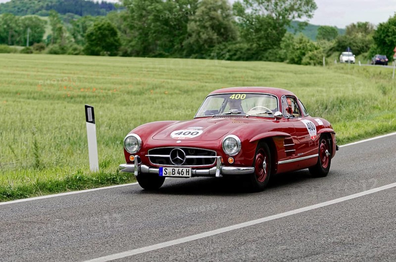 The red Mercedes classic car continues its journey on the sweeping country road, classic car, car race, Mille Miglia, 1000 Miglia, 2015, Tuscany, Rome Lake Garda, Italy