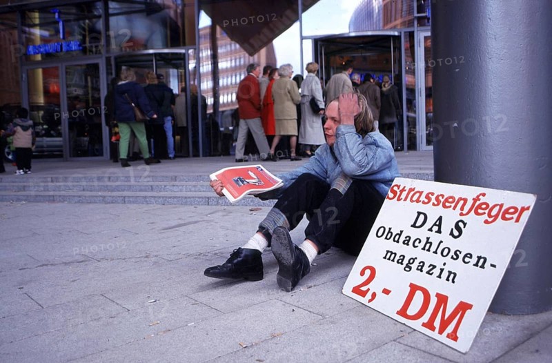 Berlin, DEU, 18.10.1998 -- Chris, seller of a homeless magazine Straßenfeger, sits in front of the casino at Potsdamer Platz arcades. (poverty)