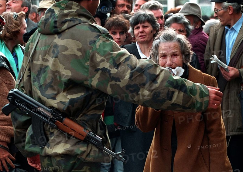 BIH, Bosnia, Sarajevo, 16.09.1992, woman is held back by a bus evacuating people from Sarajevo
