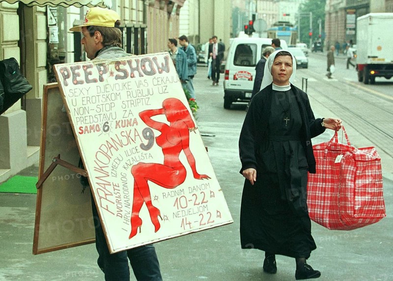 HRV, Zagreb, 01.05.1995 -- A Catholic nun meets a sex shop advertiser in Zagreb. -- A catholic now passes an advert for a sex show in downtown Zagreb.   Eastern Europe, Eastern Europe, Balkans, Croatia
