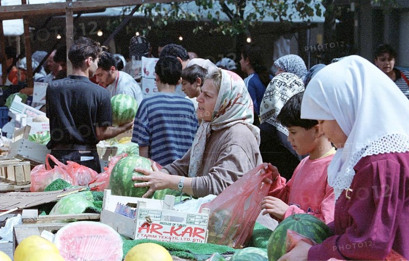 Berlin, DEU, 10.06.1998 -- Hustle and bustle on a Turkish market, salespeople wearing headscarves at a melon stand. (Retail, fruit)
