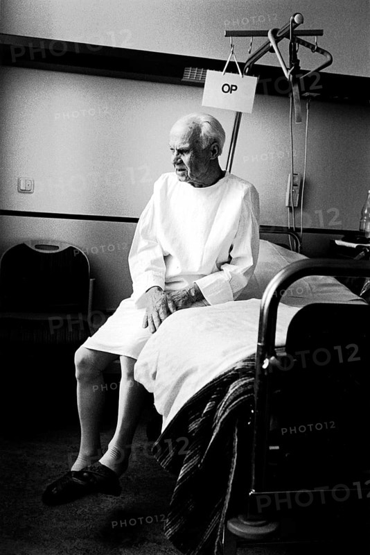 Berlin, DEU, 17.05.1998 -- ENT department, a patient (82 years old) sits on his hospital bed with an OP sign. (hospital, operation)