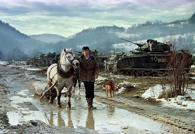 BIH, Tuzla, 01.01.1996 -- A Bosnian farmer pulls his horse past the base camp of American IFOR soldiers. -- A farmer passes a compound of U.S. IFOR troops in the mountains near Tuzla, as the American advance team deploys.   Bosnia Hercogovina, Eastern Europe