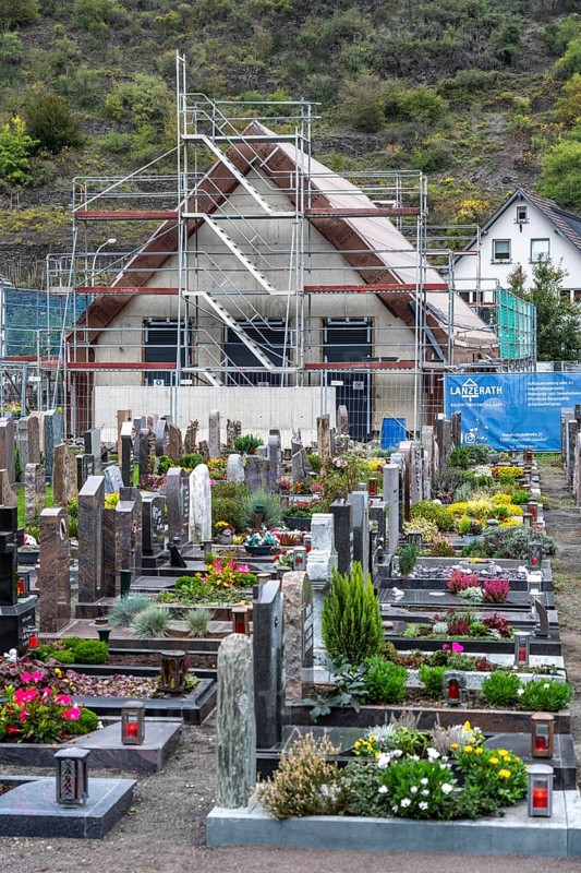 Reconstruction in the Ahr Valley, after the flood of July 2021, buildings that have not yet been renovated or demolished can be found in many places, but most buildings have now been repaired or rebuilt, restored cemetery, new cemetery hall under construction, near Altenahr, Rhineland-Palatinate