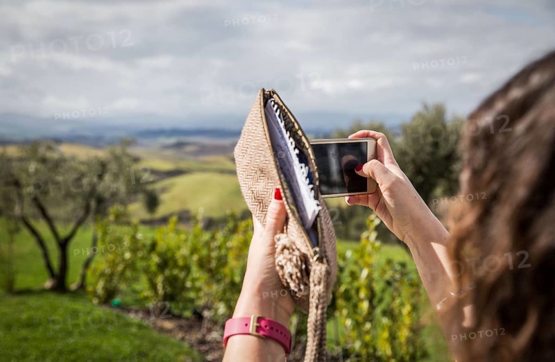 ITA Italy Castelfalfi A woman takes a photo with her smartphone on the hotel terrace