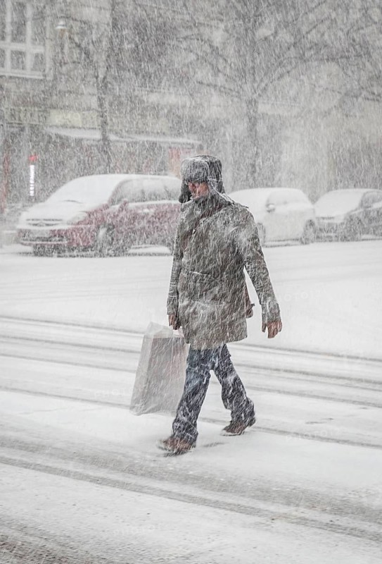 DEU Germany Germany Berlin People in the city during a snow shower.Pedestrian crosses snowy road