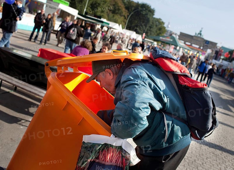 DEU Germany Berlin A collector checks the garbage cans for recyclable materials. Scene on the eve of the 20th anniversary of German reunification on the festival mile in Berlin. Germany Berlin A poor digs in a dustbin at the party for the reunification. Scene from the public party one day ahead of the celebration marking the 20th anniversary of the German reunification