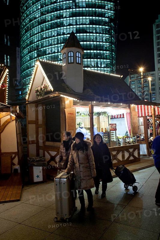 Berlin 2010-11-24 tourists with suitcases at the Christmas market at Potsdamer Platz DEU Berlin 2010-11-24 Asian tourists cross the Christmas market at Potsdamer Platz