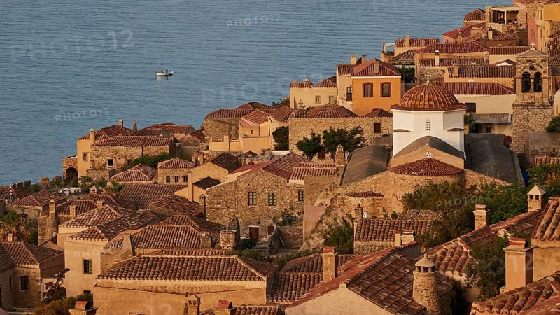 Soft morning light, Holy Church of the Virgin Mary Myrtidiotissa (or Kritikias), view of a historic seaside fishing village with tiled roofs and a small boat in the water, Monemvasia, Monemvassia, Malvasy, Byzantine small town, rocky island, fortress, Laconia, Peloponnese, peninsula, Greece
