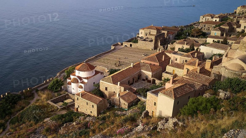Drone shot, Holy Church of the Virgin Mary Chrysaphitissa, historic coastal village with church and dome, surrounded by traditional architecture, Monemvasia, Monemvassia, Malvasy, Byzantine small town, rocky island, fortress, Laconia, Peloponnese, peninsula, Greece