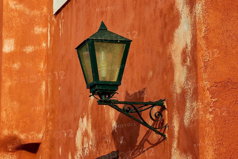 A green lantern hangs on a rust-tinted wall with distinct texture, Monemvasia, Monemvassia, Malvasy, small Byzantine town, rocky island, fortress, Laconia, Peloponnese, peninsula, Greece