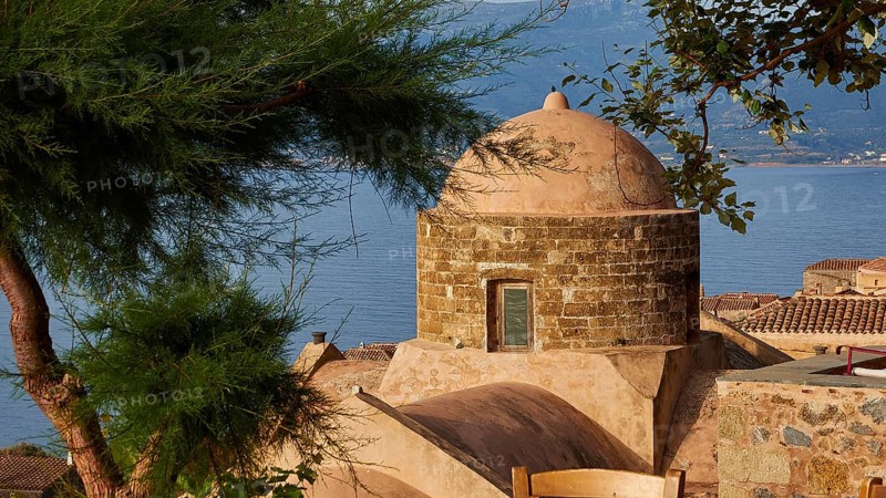 Soft morning light, view over a dome and the sea, framed by green trees and tiled roofs, Monemvasia, Monemvassia, Malvasy, small Byzantine town, rocky island, fortress, Laconia, Peloponnese, peninsula, Greece