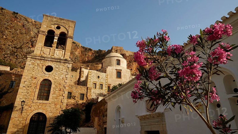 Soft morning light, Holy Church of Christ in Chains, Elkomenos Christos, Blooming oleanders in front of a historic building and a church under clear sky, Monemvasia, Monemvassia, Malvasy, Byzantine small town, rocky island, fortress, Laconia, Peloponnese, peninsula, Greece