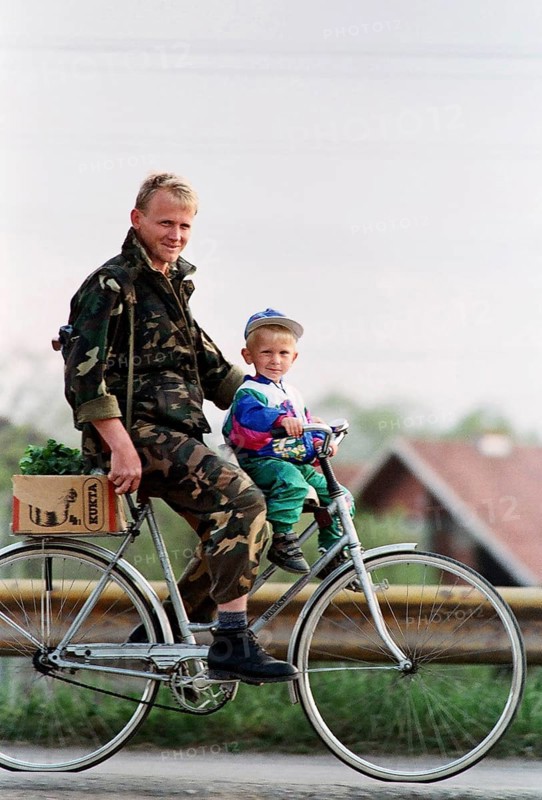 BIH, Bosnia, Tuzla, 23.08.1994 A Bosnian soldier rides a bicycle with his son