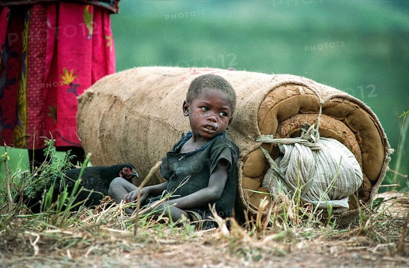TZA Tanzania scene in the Benaco Camp refugee camp, to which up to 500, 000 Rwandan Tutsis fled the genocide in their country. Refugee child is leaning on a mattress next to a chicken. TZA Tanzania Scene at the Benaco Camp, where an estimate of 500, 000 Rwandan Tutsi refugees fled the genocide in their country. Refugee Kid Rests Next to a Mattress