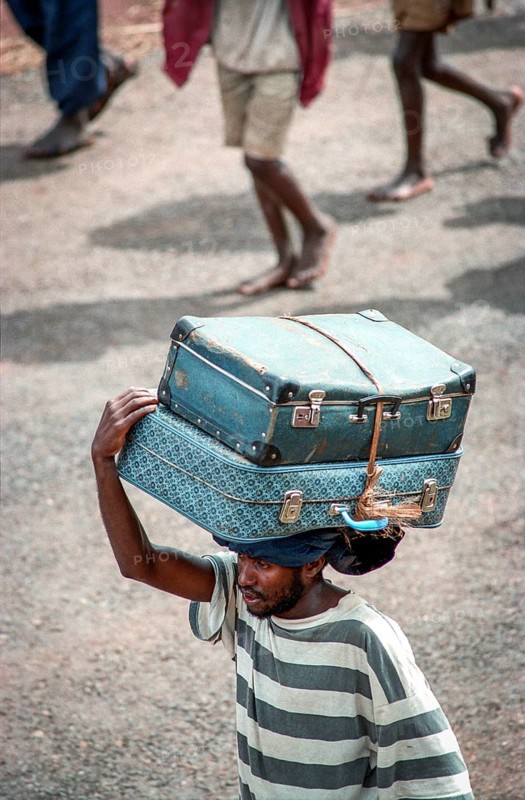 TZA Tanzania scene in the Benaco Camp refugee camp, to which up to 500, 000 Rwandan Tutsis fled the genocide in their country. A refugee carries two suitcases on his head. TZA Tanzania Scene at the Benaco Camp, where an estimate of 500, 000 Rwandan Tutsi refugees fled the genocide in their country. A man carries two suitcases on his head