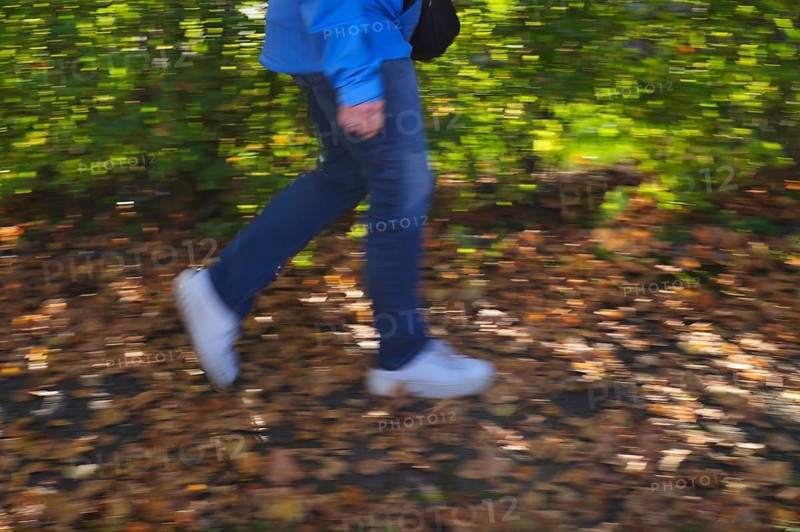 Person, woman, walks on sidewalk full of autumn leaves, autumn, leaves lying on sidewalk, movement effect, blurred, Stuttgart, Baden-Württemberg, Germany