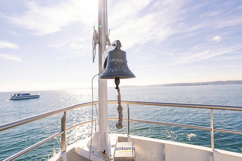 Ship bell aboard a boat on a calm sea under sunny sky, boat trip, Lake Constance, Germany