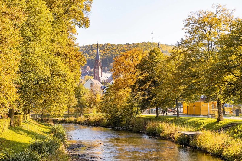 Autumn river landscape with a church and colorful trees in the background, Nagold, Black Forest, Germany