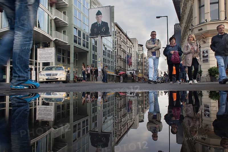 DEU Germany Germany Berlin Tourists at Checkpoint Charlie reflecting in a puddle after rain