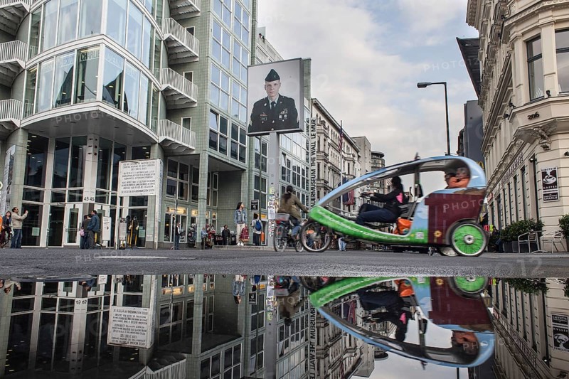 DEU Germany Germany Berlin Tourists at Checkpoint Charlie reflecting in a puddle after rain