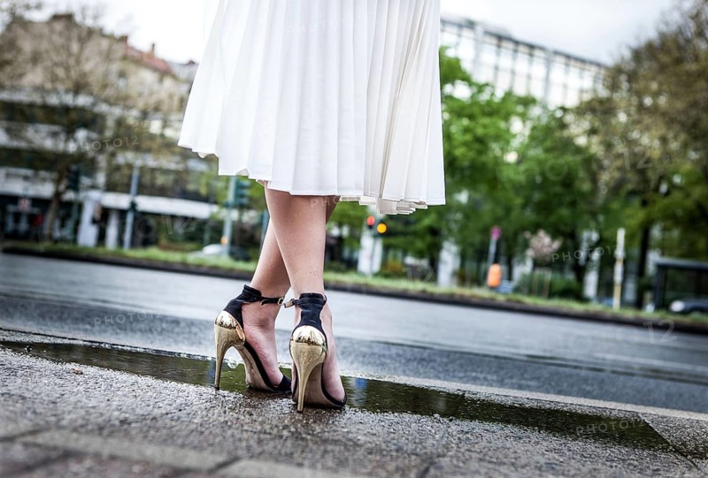 DEU Germany Germany Berlin Woman with shoes with shiny golden heels standing in a water poop on Spichernstraße