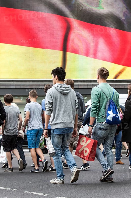 DEU Germany Germany Berlin Passers-by in front of a projection screen on Kurfürstendamm, on which a commercial featuring a large German flag is being broadcast