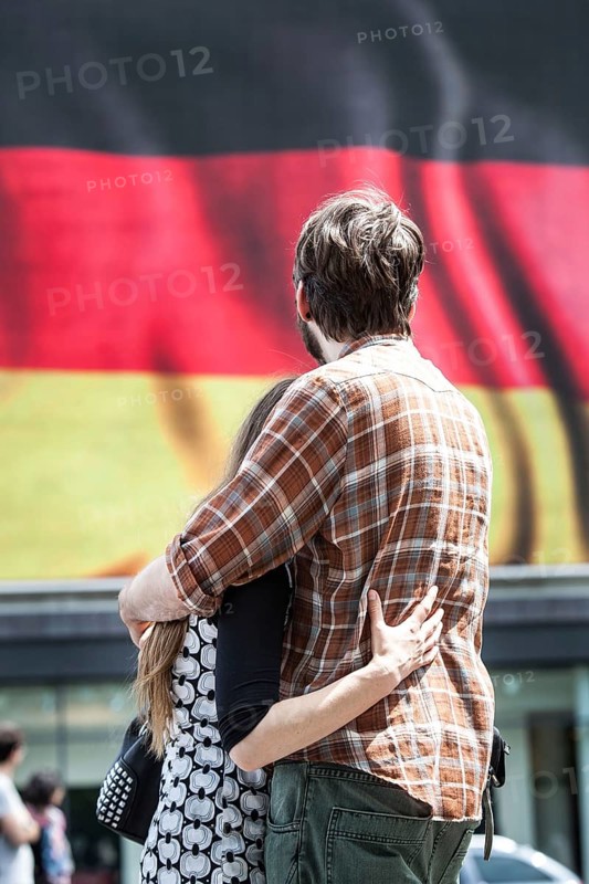 DEU Germany Germany Berlin Passers-by in front of a projection screen on Kurfürstendamm, on which a commercial featuring a large German flag is being broadcast