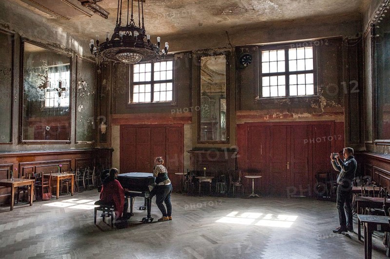 DEU Germany Germany Berlin Visitor films two woman playing a piano in the Hall of Mirrors at Clärchen's Ballhaus in Mitte
