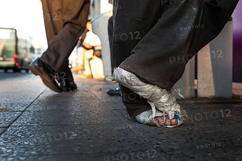 DEU Germany Germany Berlin Homeless person with plastic bag and feet connected to plastic at a bus stop on Potsdamer Platz