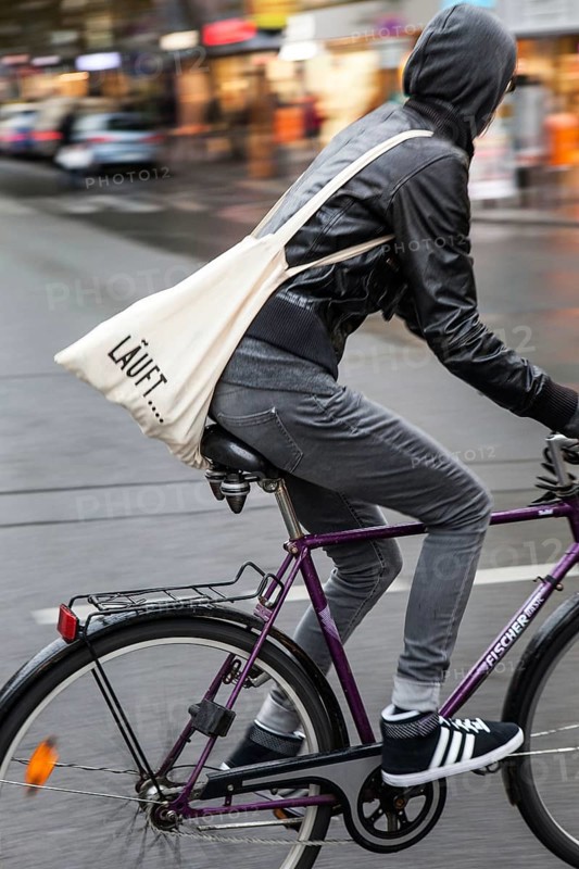 DEU Germany Germany Berlin female cyclist with cloth bag crosses a street in the capital