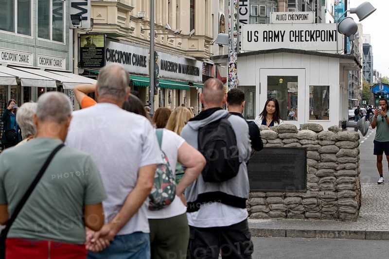 Tourists at Checkpoint Charlie queue for a souvenir photo, Berlin, Germany