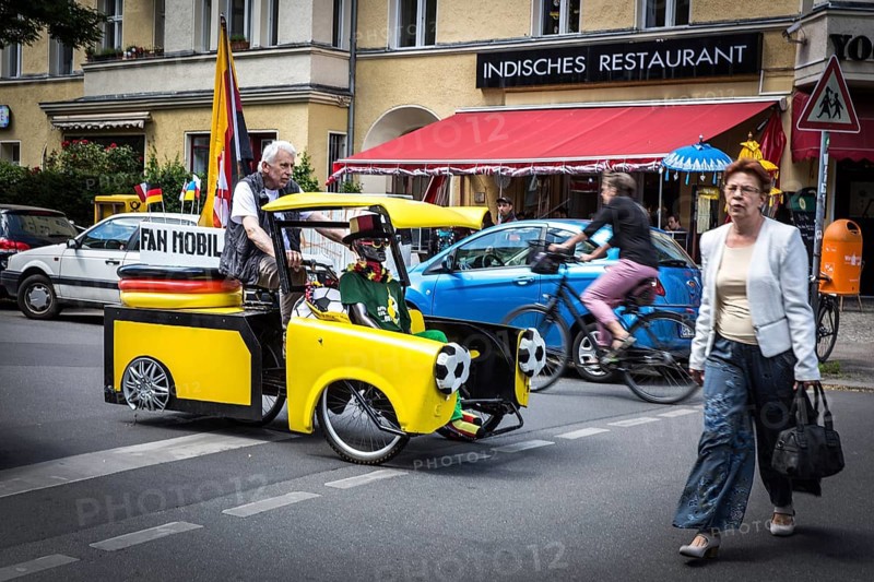 DEU Germany Germany Berlin A man drives through Schöneberg in a self-made European championship fanmobile, a bicycle rickshaw. The van can be rented