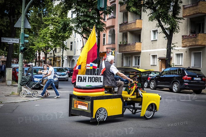 DEU Germany Germany Berlin A man drives through Schöneberg in a self-made European championship fanmobile, a bicycle rickshaw. The van can be rented
