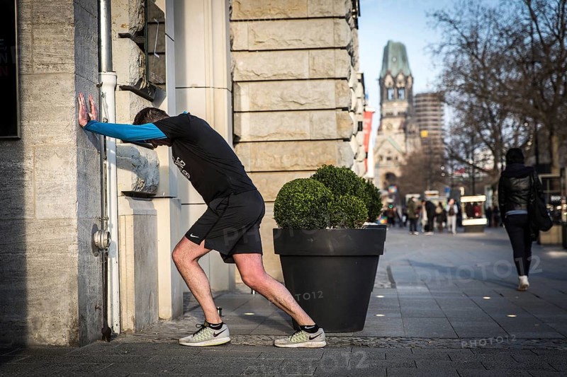 DEU Germany Germany Berlin A jogger does gymnastics in front of an Apple shop display case on Kudamm