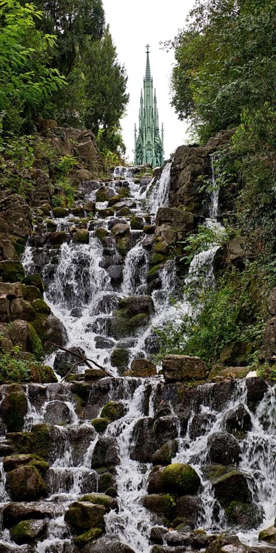 Artificial waterfall in Victoria Park, with the national monument on Kreuzberg in the background, Berlin-Kreuzberg, Germany