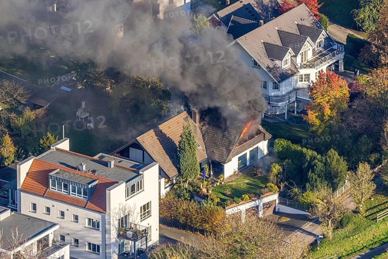 Several callers reported a fire with heavy smoke on Bergerstraße in Mülheim-Menden at 2.57 pm today, Saturday. When the first emergency services arrived, they discovered that the roof truss of a two-storey residential building was fully engulfed in flames. Due to the expected long and intensive operation, a full alarm was immediately sounded for the volunteer fire brigade. There were no residents in the house. Firefighters from the professional fire brigade immediately began fighting the fire from the inside and using a turntable ladder. As the operation progressed, they were supported by colleagues from the Heißen fire brigade of the volunteer fire brigade. Once the actual fire had been extinguished, the post-extinguishing work proved to be quite complex and lengthy. Parts of the roof have to be removed in order to reach any remaining embers. The ongoing operation involved two fire engines, several special and command vehicles from the professional fire brigade as well as vehicles fro...
