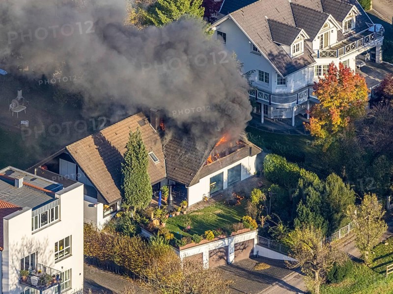 Several callers reported a fire with heavy smoke on Bergerstraße in Mülheim-Menden at 2.57 pm today, Saturday. When the first emergency services arrived, they discovered that the roof truss of a two-storey residential building was fully engulfed in flames. Due to the expected long and intensive operation, a full alarm was immediately sounded for the volunteer fire brigade. There were no residents in the house. Firefighters from the professional fire brigade immediately began fighting the fire from the inside and using a turntable ladder. As the operation progressed, they were supported by colleagues from the Heißen fire brigade of the volunteer fire brigade. Once the actual fire had been extinguished, the post-extinguishing work proved to be quite complex and lengthy. Parts of the roof have to be removed in order to reach any remaining embers. The ongoing operation involved two fire engines, several special and command vehicles from the professional fire brigade as well as vehicles fro...