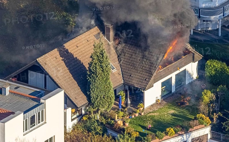 Several callers reported a fire with heavy smoke on Bergerstraße in Mülheim-Menden at 2.57 pm today, Saturday. When the first emergency services arrived, they discovered that the roof truss of a two-storey residential building was fully engulfed in flames. Due to the expected long and intensive operation, a full alarm was immediately sounded for the volunteer fire brigade. There were no residents in the house. Firefighters from the professional fire brigade immediately began fighting the fire from the inside and using a turntable ladder. As the operation progressed, they were supported by colleagues from the Heißen fire brigade of the volunteer fire brigade. Once the actual fire had been extinguished, the post-extinguishing work proved to be quite complex and lengthy. Parts of the roof have to be removed in order to reach any remaining embers. The ongoing operation involved two fire engines, several special and command vehicles from the professional fire brigade as well as vehicles fro...