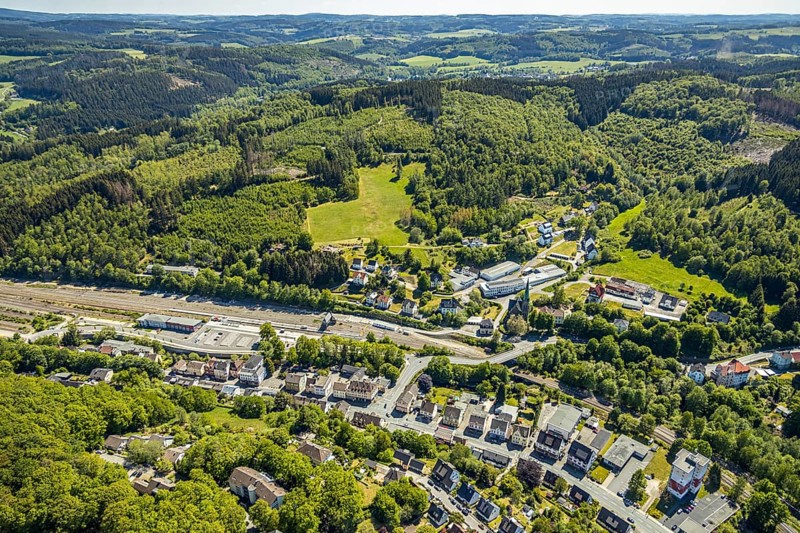 Aerial view, Brügge district, Lüdenscheid-Brügge railway station, Lüdenscheid fire brigade, Brügge equipment depot, Evang. Kreuzkirche Brügge, Lüdenscheid, Märkischer Kreis, Sauerland, North Rhine-Westphalia, Germany, place of worship, railway tracks, railway station, station forecourt, fire fighter, fire protection, fire station, bridge signal box, federal road B54, DE, Deutsche Bahn AG, Europe, distant view, fire engine, fire brigade, fire station, fire engine, commercial area, commercial use, religious community, place of worship, property tax, green trees, hilly landscape, real estate, church, parish, denomination, district town, aerial view, aerial photography, aerial photography, fire engine, tenement houses, religion, separation station, overview, bird's eye view, Volmetalbahn, meadows and fields, living and life, residential buildings, birds-eyes view, green lung, overview